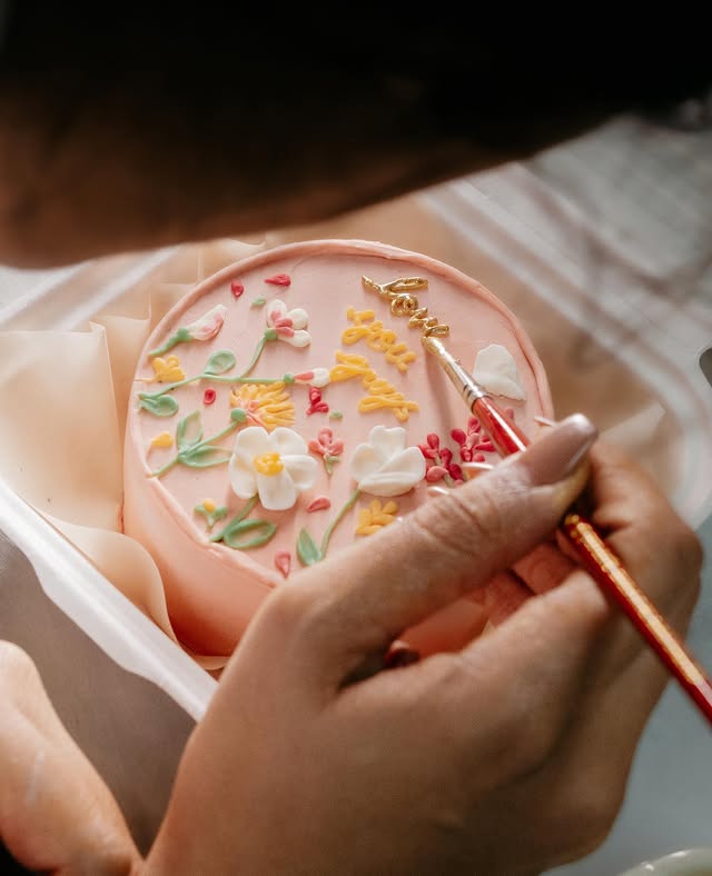 Chef Sneha hand-piping floral detail onto a bento cake